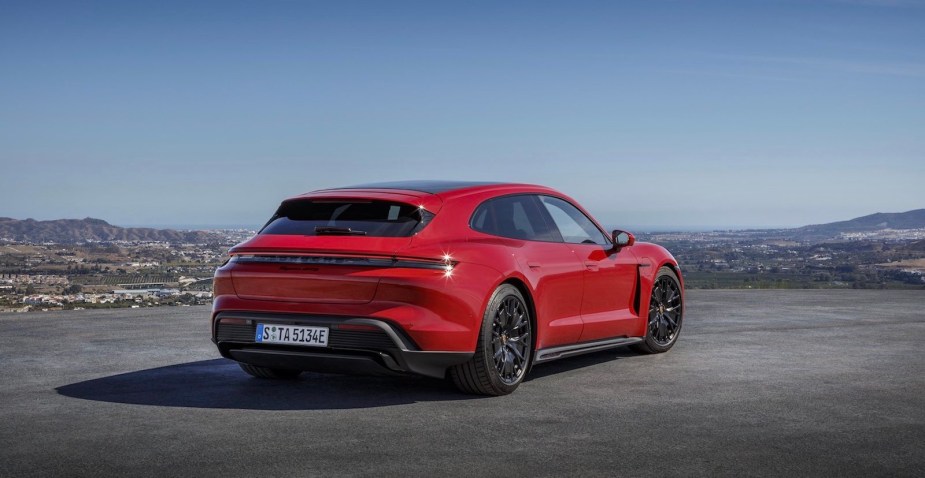 Red electric Porsche parked on a mountain top above a city in a valley.