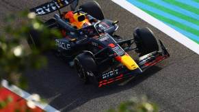 A drone captures an image of Max Verstappen driving a Red Bull F1 car.