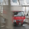 Red cargo truck with a white box crosses a bridge on a highway