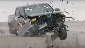 Green Rivian R1T electric pickup truck smashes through a guard rail barrier