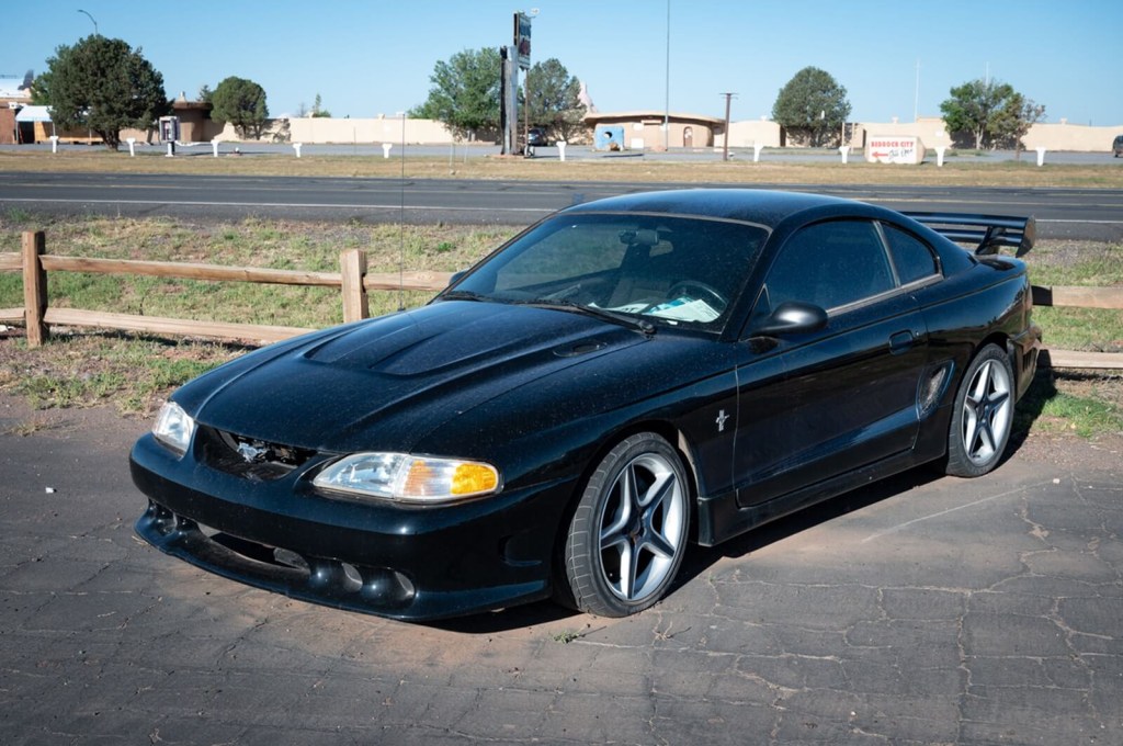 A black SN95 Ford Mustang in a parking lot.