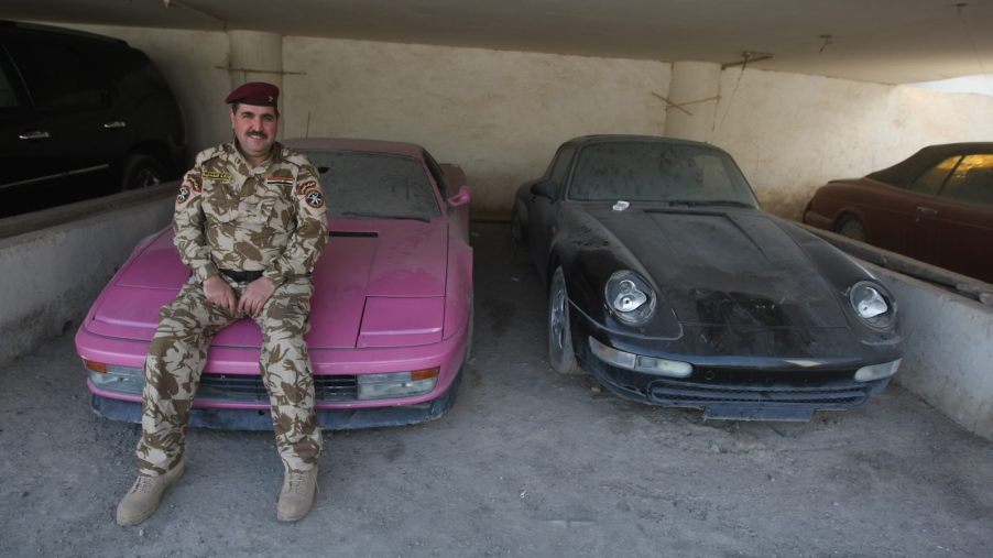 Policeman sits on the hood of a Ferrari Testarossa seized from Uday and Saddam Hussein.