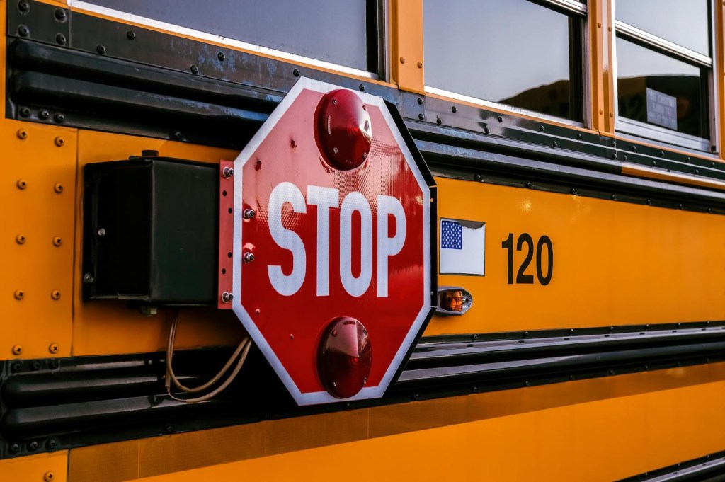 The red stop sign on the side of a yellow school bus.