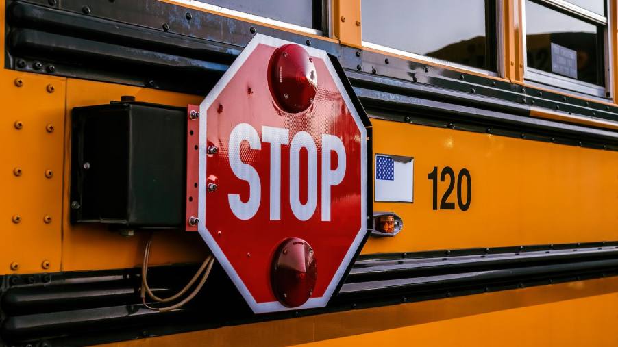 The red stop sign on the side of a yellow school bus.