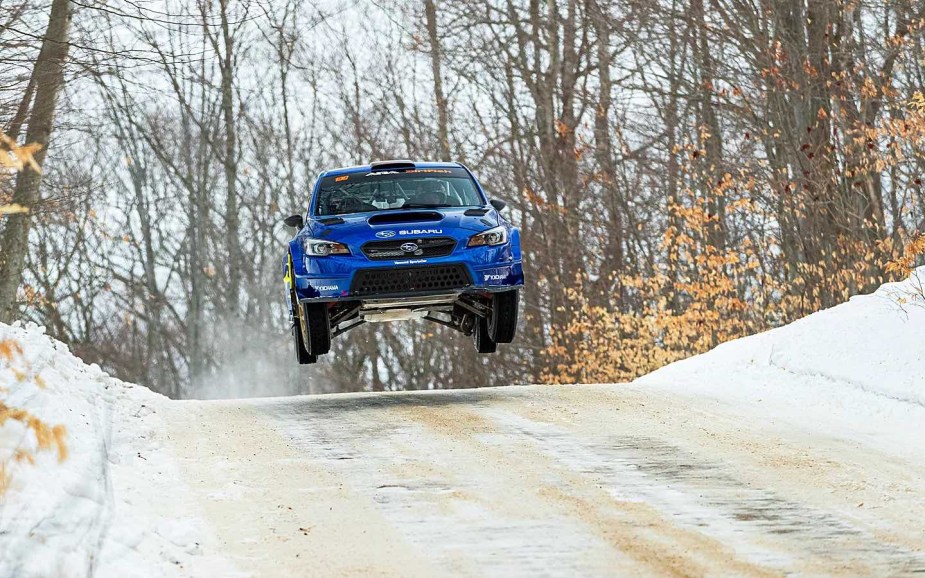 Blue Travis Pastrana Subaru WRX takes a jump at the Sno*Drift rally.