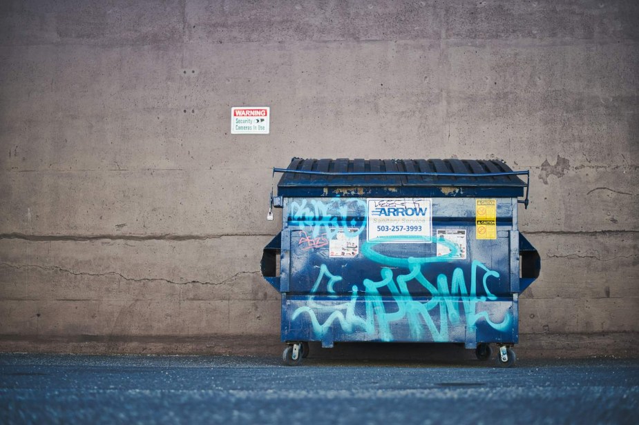 Dumpster against a brick wall.