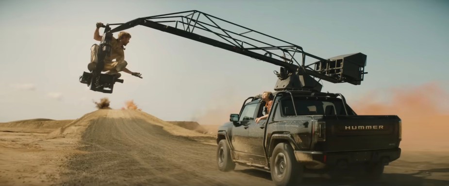 Ryan Gosling hangs off a crane on a Hummer EV during "The Fall Guy" movie.