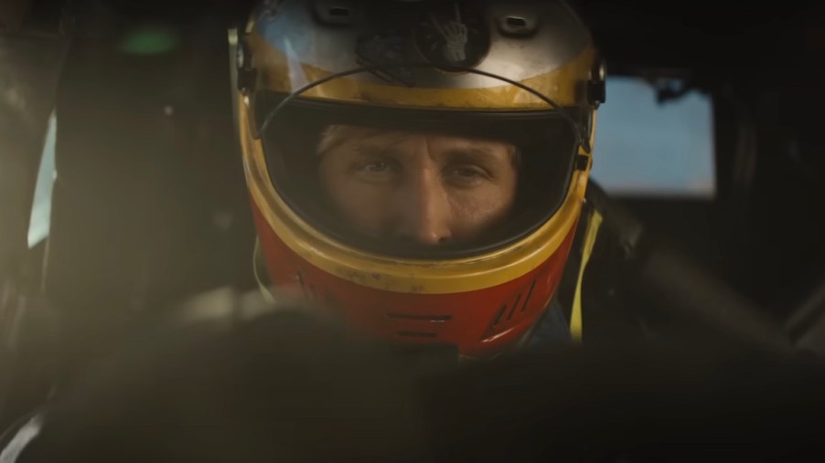 Ryan Gosling wearing a race car helmet in a car during "The Fall Guy" film.