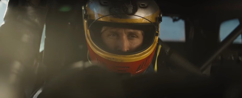 Ryan Gosling wearing a race car helmet in a car during "The Fall Guy" film.