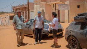James May, Jeremy Clarkson, and Richard Hammond pose next to a Maserati GranCabrio and an Aston Martin DB9 in Mauritania.