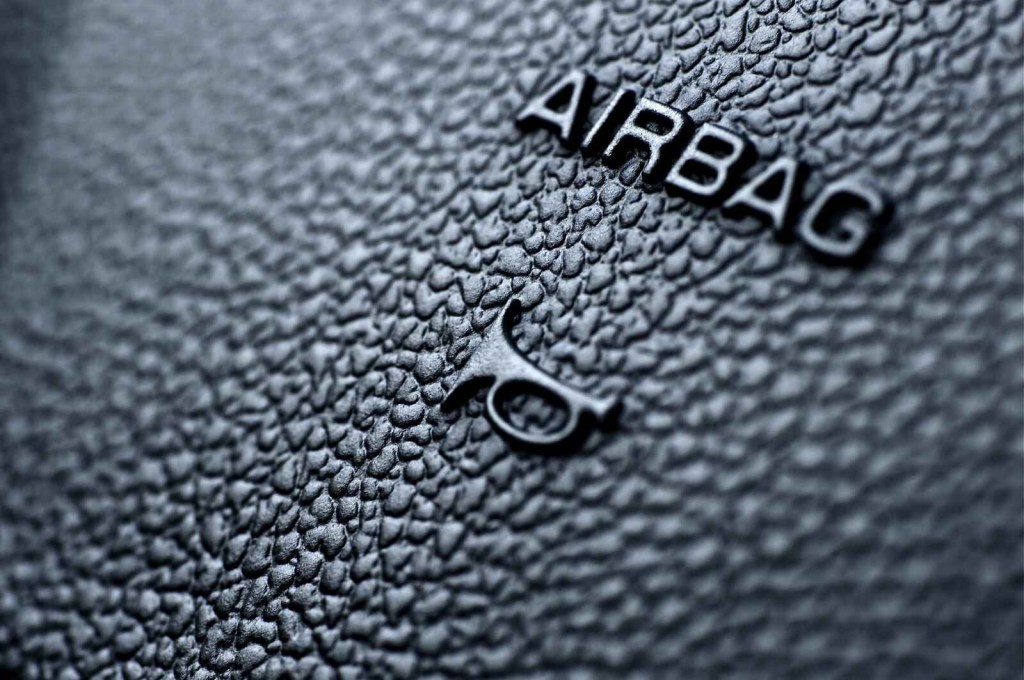 The words "AIRBAG" and air horn icon are shown on a black car steering wheel in close view