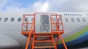 The left MED plug on Alaska Airlines Flight 1282 shown covered in a plastic sheeting with an orange metal staircase positioned in front of it