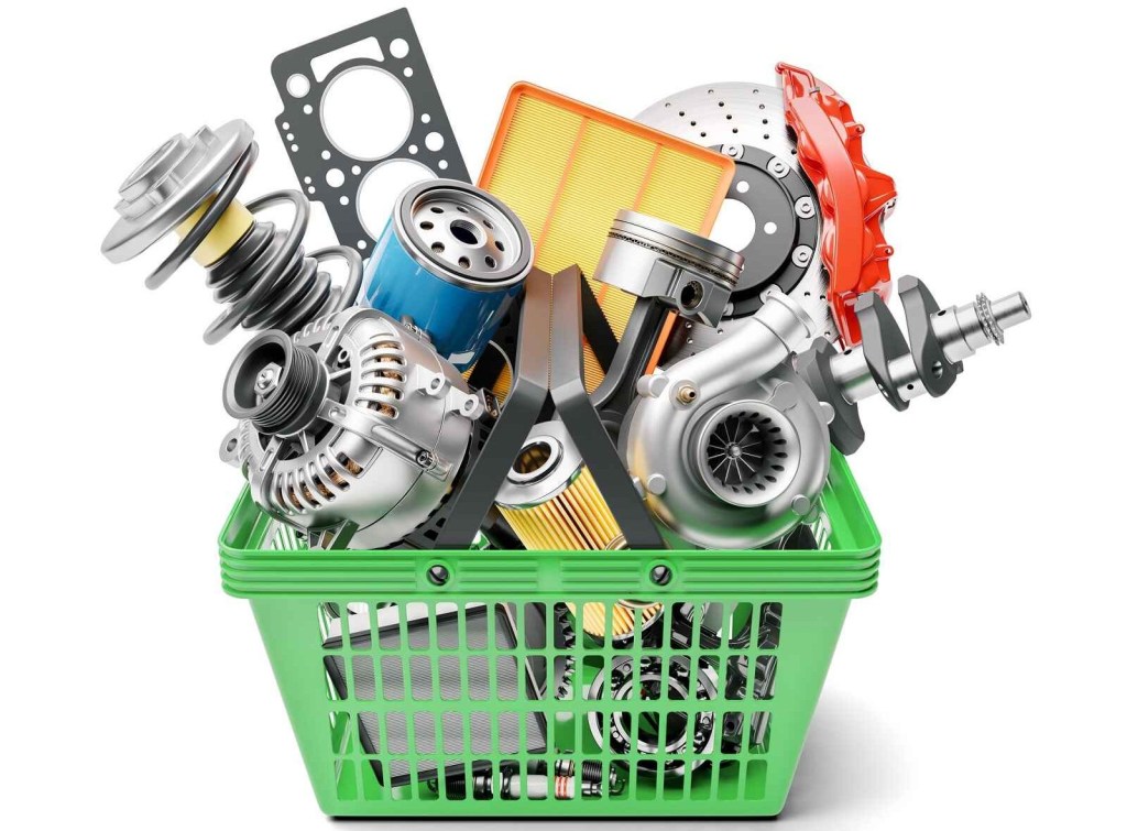 A green shopping basket is filled with unboxed car parts white background