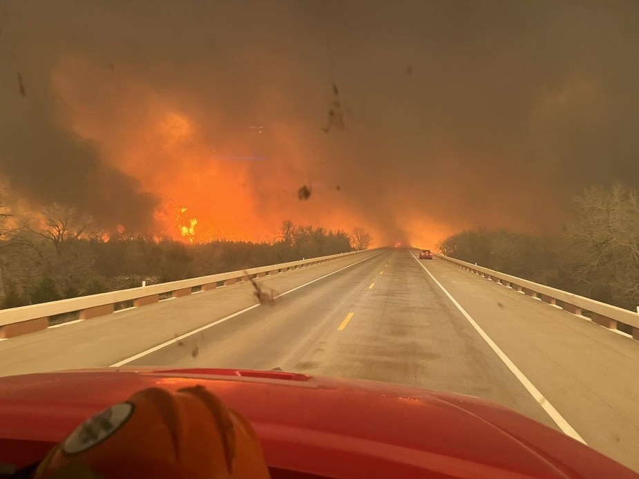 First-person view from inside a Texan fire truck driving on a paved road towards a wildfire