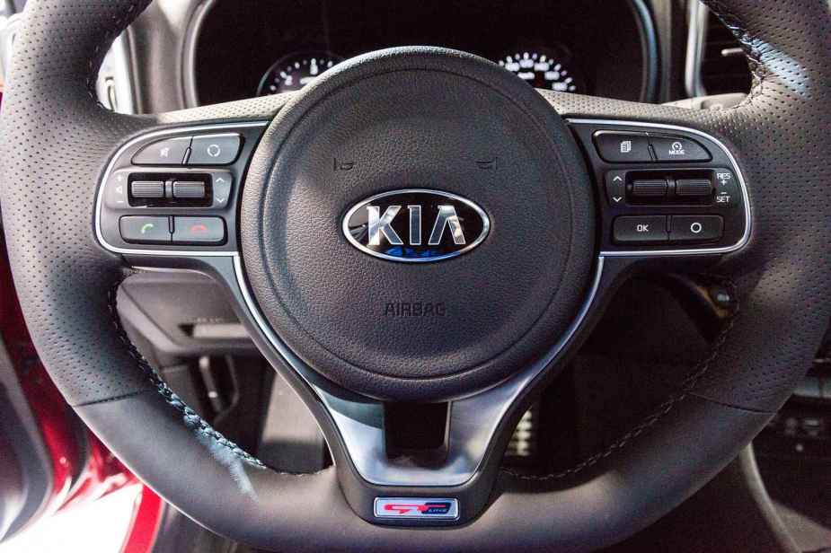 A black Kia steering wheel shown in close view logo centered