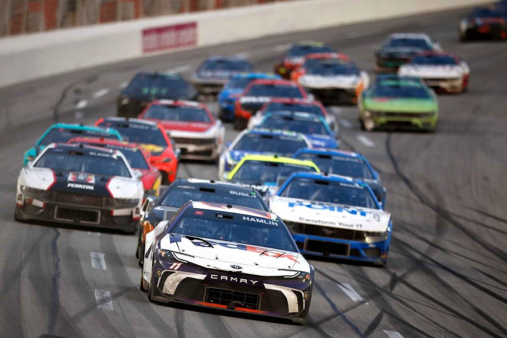 NASCAR cars in a large group on the track during the 2024 Cup Series Ambetter Health 400
