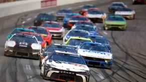 NASCAR cars in a large group on the track during the 2024 Cup Series Ambetter Health 400
