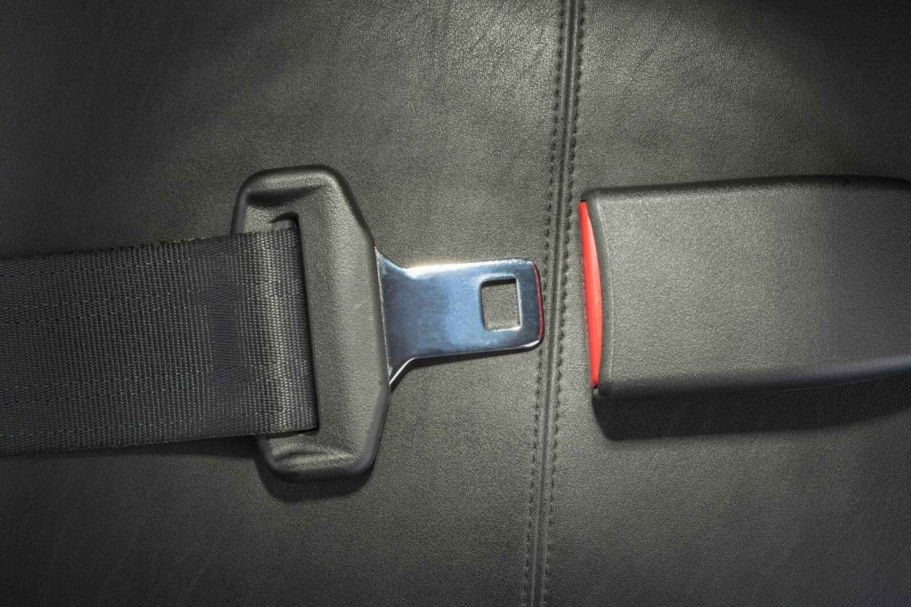 An unbuckled seat belt assembly is shown in a black leather car interior