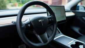 A black Tesla steering wheel is shown in close up