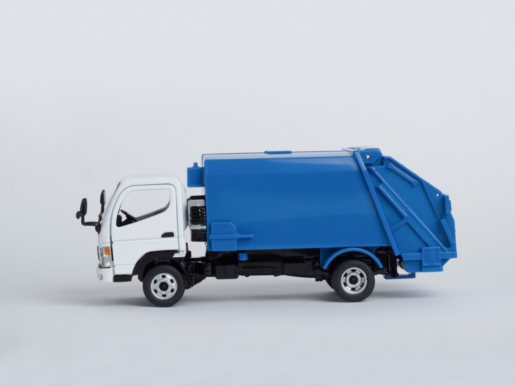 A blue and white toy garbage truck parked in left profile view