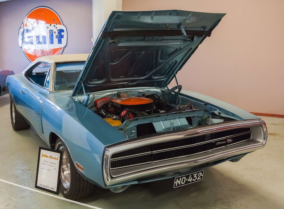 Blue 1970 Dodge Charger in a museum with its hood up, showing off a Six Pack V8 engine
