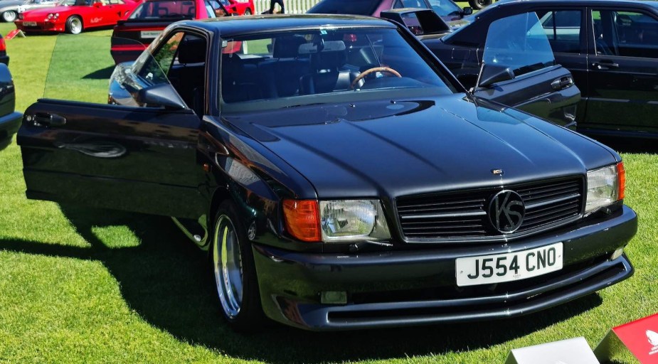 Black Mercedes coupe parked on a grassy field during a car show.