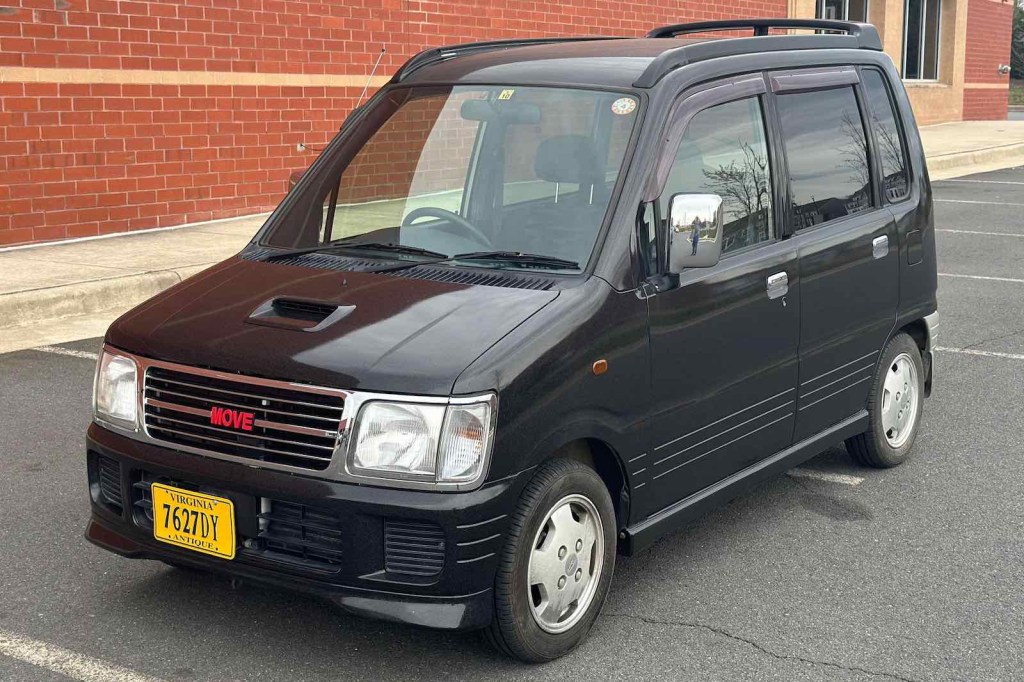 Black Daihatsu Move parked in front of a brick wall.