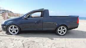 Side view of a modified VW Jetta pickup truck parked on a beach.
