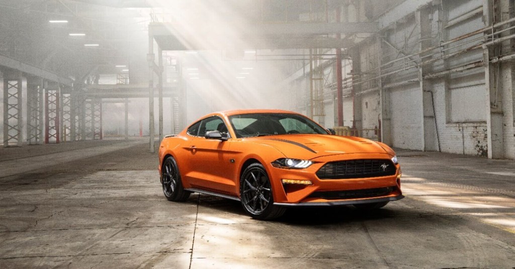 An orange Ford Mustang EcoBoost High Performance in a warehouse. 