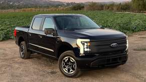 Black 2022 Ford F-150 Lightning electric truck posed next to a field.