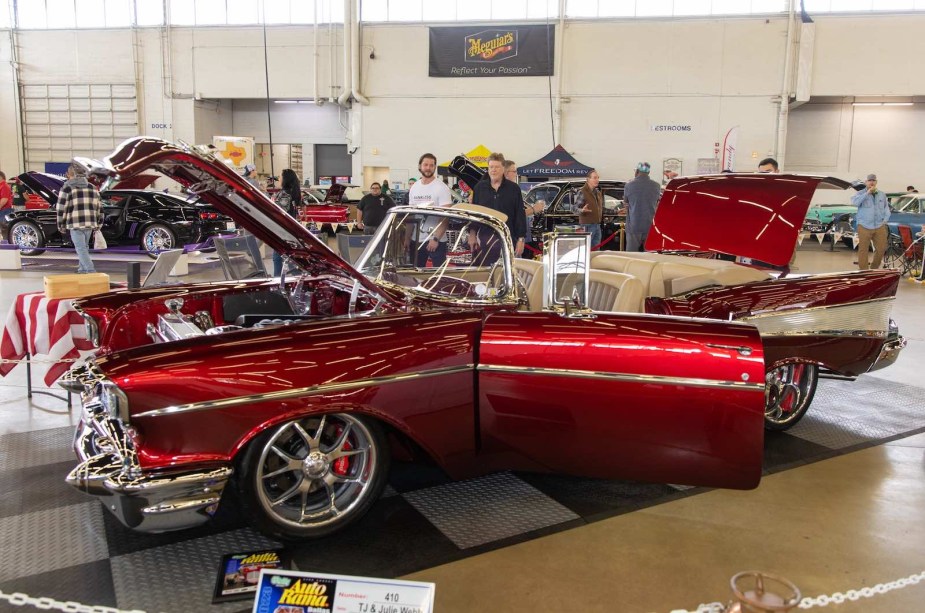 Red 1957 Chevy convertible at an indoor car show.