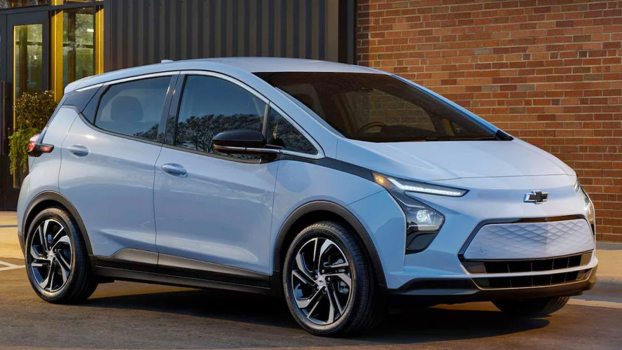 Light Blue 2023 Chevy Bolt EV posed in front of a building.