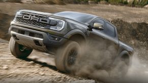 2024 Ford Ranger Raptor off-road truck clmbing to the top of a dirt-covered hilll.