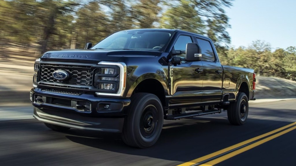 Black 2024 Ford Super Duty driving on a road.
