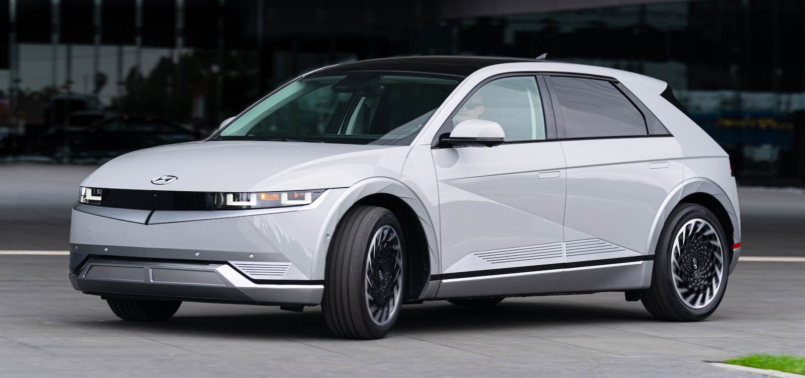 Whit Hyundai Ioniq 5 EV crossover SUV driving around a corner.