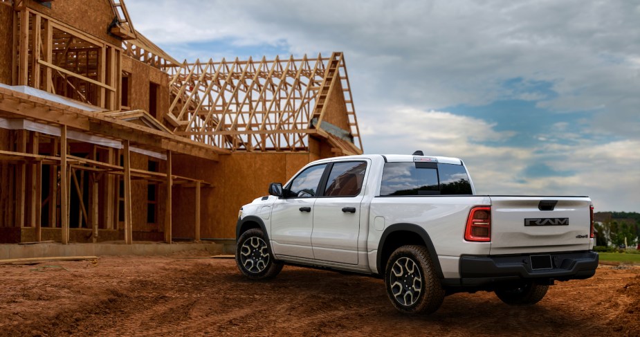 White electric Ram pickup truck parked in front of a construction site.