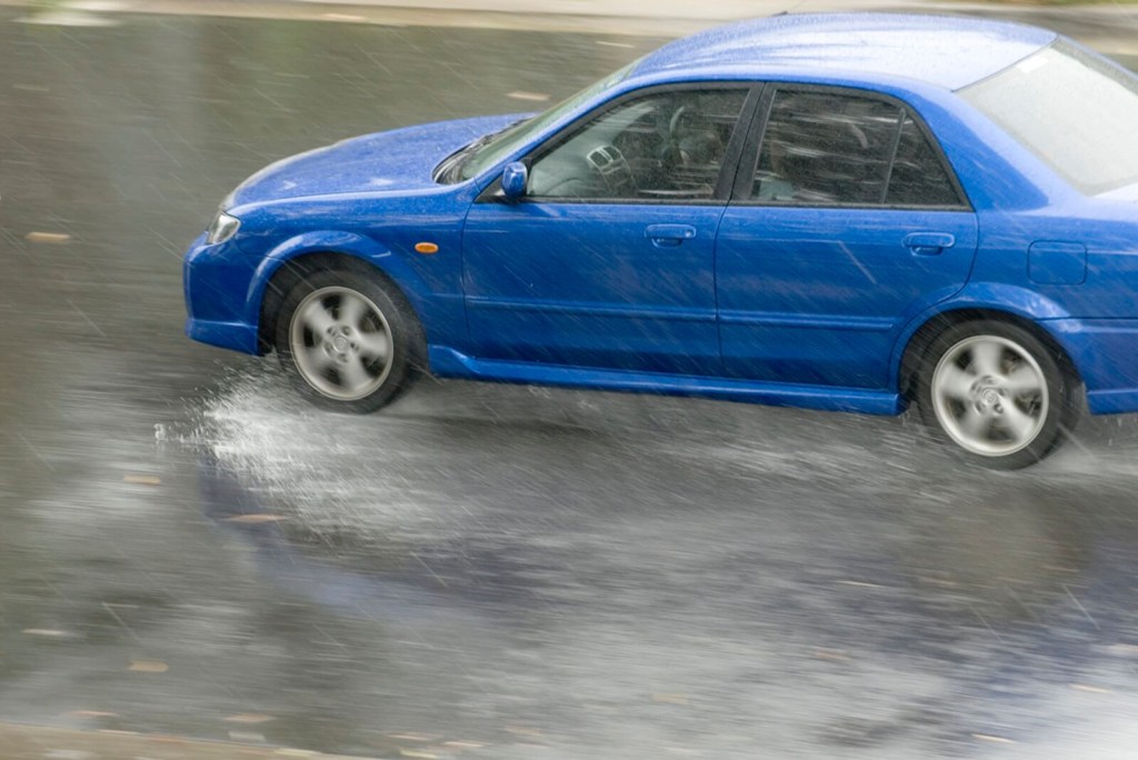 A blue Mazda sedan displaces water to combat hydroplaning. 
