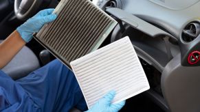Mechanic with gloves holds up a dirty and a clean cabin air filter.