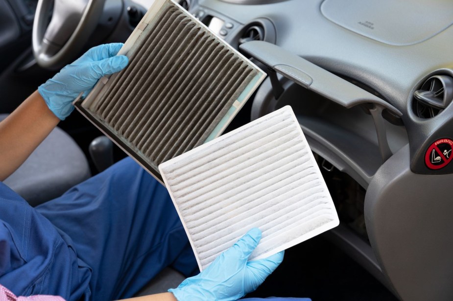 Mechanic with gloves holds up a dirty and a clean cabin air filter.