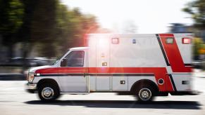 An operator drives an ambulance with sirens and lights used to clear traffic.