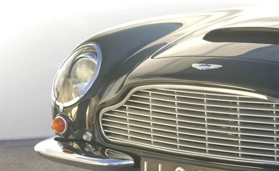 A closeup shot reveals an Aston Martin DB6, a GT car owned by Mick Jagger, Paul McCartney, and King Charles III.