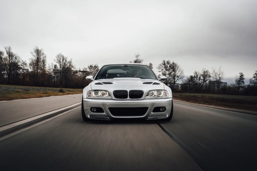 Front grille of a silver BMW M3 from the E46-generation 3 Series racing down the road.