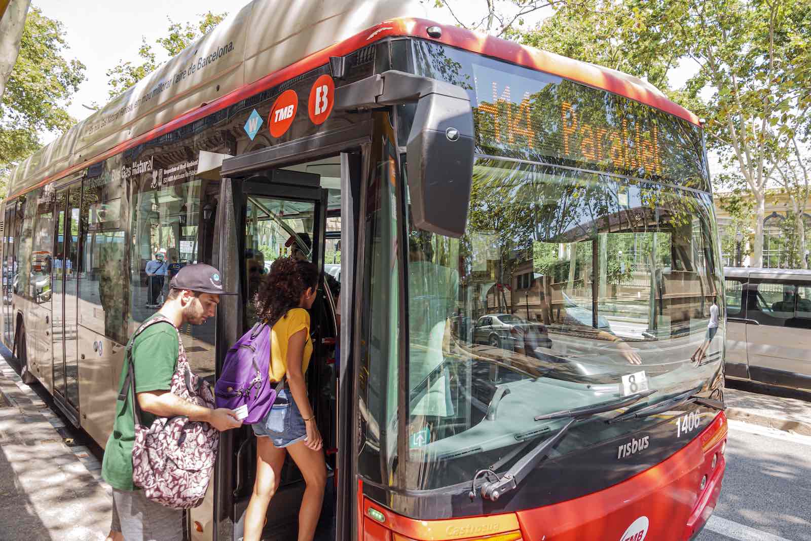 Passengers board a red bus in Barcelona
