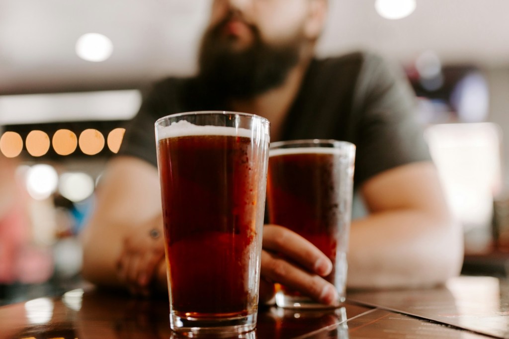 A man sits in a bar with two beers in front of him.