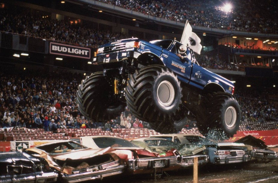 Bigfoot 7 monster truck performs car crushing in a stadium crowded with people.