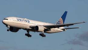 A United Airlines flight, a Boeing 777-200, cruises with its landing gear tires out.