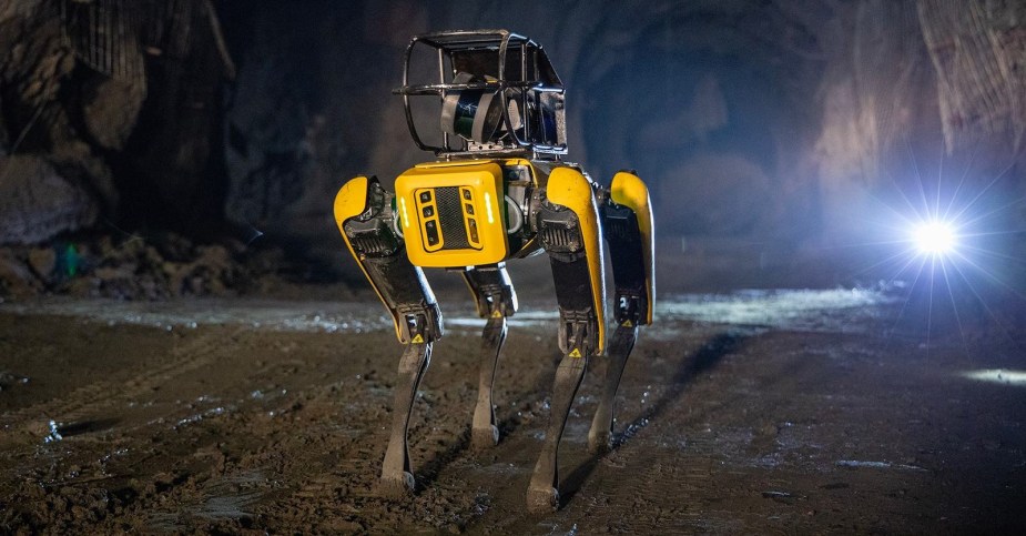 A yellow robot with four legs walks through a cave.