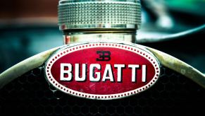 The Bugatti logo on the copper horseshoe radiator of a vintage race car.