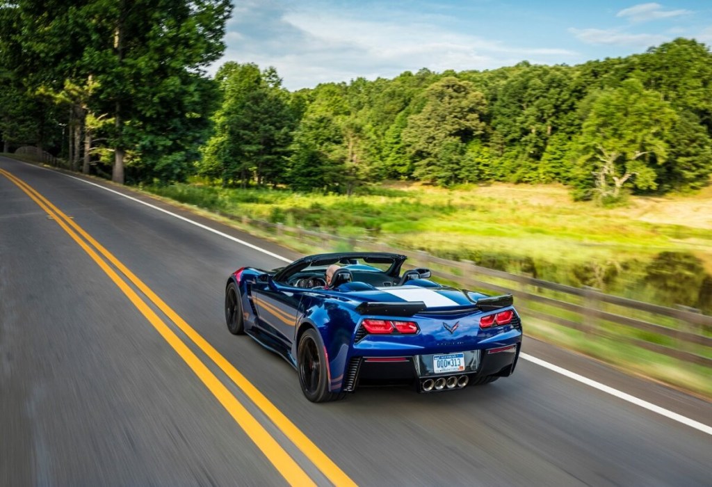 A blue C7 Chevrolet Corvette Convertible, like the one in 'The Family Plan' cruises a back road. 
