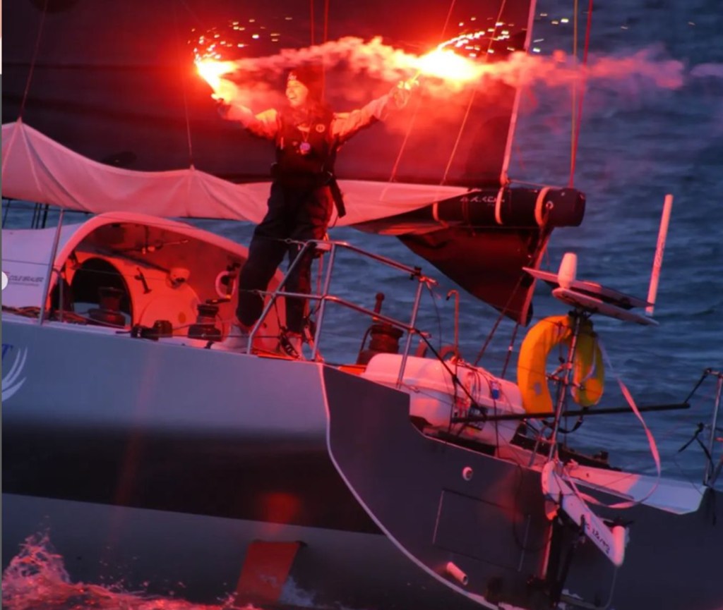 Cole Brauer waves flares aboard the 'First Light' after a sail around the world.